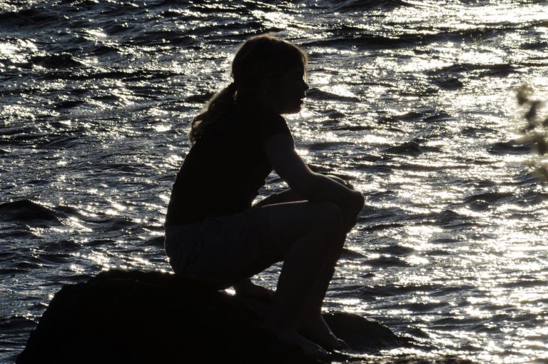 girl sitting on a stone in the river, summertime Sweden