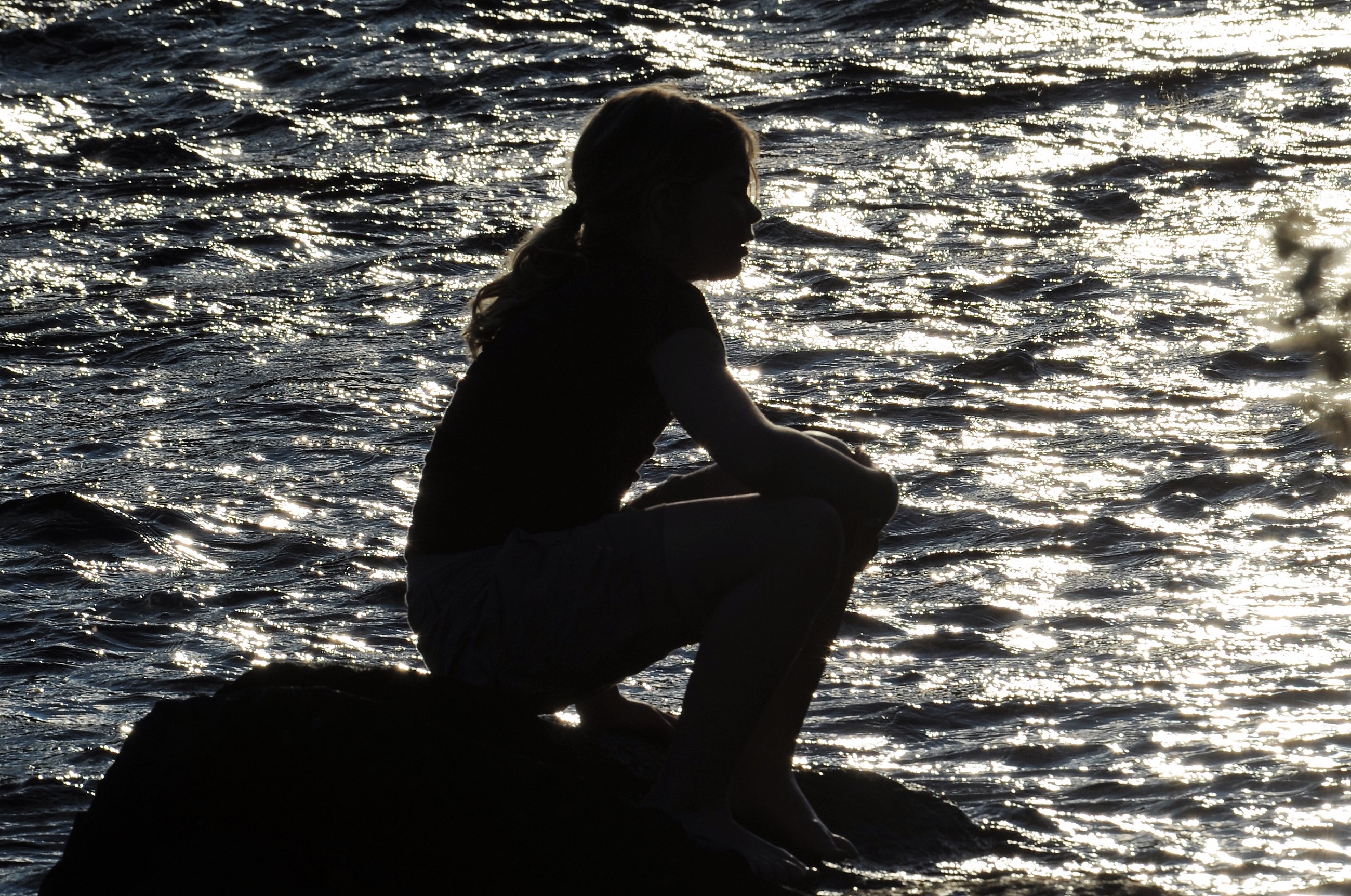 girl sitting on a stone in the river, summertime Sweden